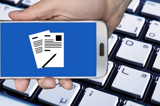 Handy mit Online-Antrag auf Bildschirm, Tastatur im Hinertgrund
